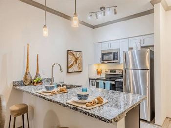 A kitchen with a granite countertop and stainless steel appliances.